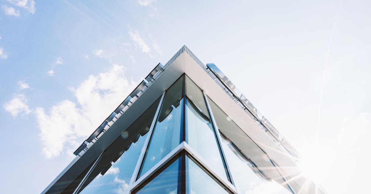 Low angle shot of a modern glass building with sun glare reflecting on its surface.